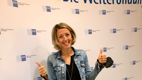 Bild von Dunja Christeit vor einer Werbewand der IHK